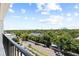 A balcony view overlooks a neighborhood road, lush greenery, city buildings, and a bright blue sky filled with fluffy white clouds at 3211 W Swann Avenue # 707, Tampa, FL 33609