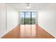 A bright bedroom features gleaming hardwood floors, a ceiling fan, a large window view, and pristine white walls at 3211 W Swann Avenue # 707, Tampa, FL 33609