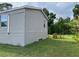 The side of the house is clad in gray siding, showing a small window, and a large green lawn at 3221 Roxborough Ave, Clearwater, FL 33762