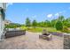Stone patio area with wicker furniture and an outdoor stone fireplace, overlooking the green space at 4633 Ballantrae Blvd, Land O Lakes, FL 34638