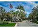 Community entrance with an American flag, palm trees and guard house at 5117 Fairway One Dr, Valrico, FL 33596