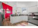 Bright kitchen with white cabinets, a colorful red accent wall, and modern appliances at 5117 Fairway One Dr, Valrico, FL 33596
