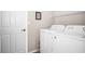 Bright laundry room features a white washer and dryer with overhead shelving and a closed door at 5117 Fairway One Dr, Valrico, FL 33596