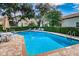 Community swimming pool featuring lounge chairs and umbrella-covered tables surrounded by lush landscaping at 5117 Fairway One Dr, Valrico, FL 33596