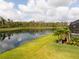 Spacious backyard with a beautiful lake view, lush greenery, and access to a screened pool at 5511 Badini Way, Palmetto, FL 34221