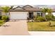 Charming single-story home with well-manicured lawn, mature landscaping, and brick-paved driveway at 5511 Badini Way, Palmetto, FL 34221