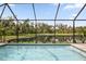Enjoy scenic views of lush greenery and a serene lake from this beautiful screened-in pool at 5511 Badini Way, Palmetto, FL 34221