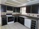 Galley kitchen features black cabinetry, white appliances, and tile flooring at 5736 116Th N Ave, Pinellas Park, FL 33782