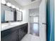 This bathroom includes a double sink vanity and a view of the bedroom with hardwood floors at 5808 Silver Moon Ave, Tampa, FL 33625