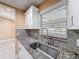 Close-up of kitchen sink with granite countertops, stylish backsplash and a window with natural light at 5808 Silver Moon Ave, Tampa, FL 33625