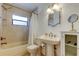 Bright bathroom featuring a pedestal sink, tub with shower, and decorative mirror at 6409 41St N Ave, St Petersburg, FL 33709