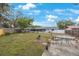A spacious backyard with green grass, mature trees, a patio set, and a glimpse of the home's exterior at 6639 Winding Oak Dr, Tampa, FL 33625