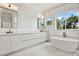 A modern bathroom featuring double vanities, a stand alone tub, and a large window at 710 W Plymouth St, Tampa, FL 33603