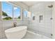 Bright bathroom featuring a sleek freestanding tub, white tiled walls, and a glass-enclosed shower at 710 W Plymouth St, Tampa, FL 33603