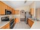 Open kitchen with stainless appliances, light tile floors and wood cabinets at 7157 Hamilton Park Blvd, Tampa, FL 33615