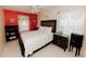Cozy bedroom featuring a plush bed, bright red accent wall, and natural light at 9852 Laurel Ledge Dr, Riverview, FL 33569