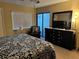 Well-lit bedroom includes a dresser with tv, comfortable seating, and large window at 105 Lakeview Way # 105, Oldsmar, FL 34677