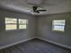 A serene bedroom showcasing neutral walls, wood flooring, a ceiling fan, and multiple windows at 11210 Mcmullen Rd, Riverview, FL 33569