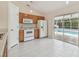 Open kitchen with wood cabinets, white appliances, and sliding door access to the screened-in pool area at 11627 Ivy Flower Loop, Riverview, FL 33578
