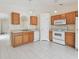 Bright kitchen featuring wood cabinets, white appliances, and white tile flooring at 11627 Ivy Flower Loop, Riverview, FL 33578