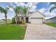 Attractive home with manicured lawn, palm trees, and a brick driveway leading to an attached two-car garage at 11904 Greenchop Pl, Riverview, FL 33579