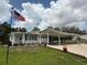 Charming single-story home featuring a long driveway, carport, and manicured lawn under a partly cloudy sky at 12021 Club House Rd, Brooksville, FL 34613