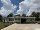 Charming single-story home featuring a long driveway, carport, and manicured lawn under a partly cloudy sky at 12021 Club House Rd, Brooksville, FL 34613
