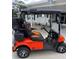 Custom orange and black golf cart featuring chrome wheels and comfortable seating at 12021 Club House Rd, Brooksville, FL 34613