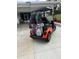 Rear view of a custom orange golf cart, featuring golf club carriers and comfortable seating at 12021 Club House Rd, Brooksville, FL 34613