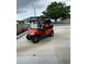 Bright orange golf cart with black seats parked in front of a well-maintained home at 12021 Club House Rd, Brooksville, FL 34613