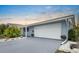 Charming blue home with a two-car garage, a concrete driveway, and a well-maintained yard at 1205 Desert Hills Dr, Sun City Center, FL 33573