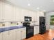 Kitchen featuring white cabinets, black appliances, and tiled countertops at 13608 Lytton Way, Tampa, FL 33624