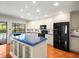 Bright kitchen featuring white cabinets, black appliances, and an island with blue countertops at 13608 Lytton Way, Tampa, FL 33624