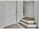 A modern entryway with neutral tones, a white paneled door, and the bottom portion of a stairway leading to the upper floors at 1402 Harbour Walk Rd, Tampa, FL 33602