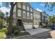 A charming three-story townhome featuring a two-car garage, a cozy entryway staircase, and a well-maintained front yard at 1402 Harbour Walk Rd, Tampa, FL 33602