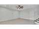 A large empty living room with tiled floors, a ceiling fan, neutral paint, and a doorway with stairs leading to another level at 1402 Harbour Walk Rd, Tampa, FL 33602