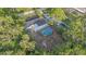 Aerial view of a home with a pool and screened-in patio surrounded by lush greenery at 15025 Shark St, Hudson, FL 34667