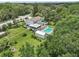 Expansive aerial view showcasing a home with a screened porch, outdoor deck, sparkling pool, and mature trees at 1709 Main St, Safety Harbor, FL 34695