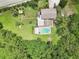 Expansive aerial view of a well-maintained home with a private pool, lush green lawn, and a cozy fire pit area at 1709 Main St, Safety Harbor, FL 34695