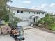 Charming two-story home featuring an attached garage, manicured yard, and golf cart parking on a paved driveway at 1709 Main St, Safety Harbor, FL 34695