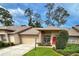 Charming single-story home featuring manicured landscaping, a two-car garage, and a welcoming red front door at 18531 Bent Pine Dr, Hudson, FL 34667