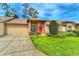 Charming single-story home featuring manicured landscaping, a two-car garage, and a welcoming red front door at 18531 Bent Pine Dr, Hudson, FL 34667