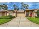 Charming single-story home featuring manicured landscaping, a two-car garage, and a welcoming red front door at 18531 Bent Pine Dr, Hudson, FL 34667