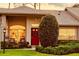 Inviting front porch featuring a bright red door with a wreath, seating, and manicured landscaping at 18531 Bent Pine Dr, Hudson, FL 34667