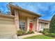 Inviting front porch featuring a bright red door with a wreath, seating, and manicured landscaping at 18531 Bent Pine Dr, Hudson, FL 34667