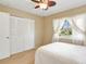 Bright bedroom with a ceiling fan, white closet doors, and a window overlooking the yard at 18702 Van Nuys Cir, Port Charlotte, FL 33948