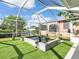 Screened lanai features a tranquil pond, artificial turf, and views of the home's exterior at 18702 Van Nuys Cir, Port Charlotte, FL 33948