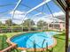 Sparkling kidney shaped pool with artificial turf, screen enclosure, and a surrounding patio at 18702 Van Nuys Cir, Port Charlotte, FL 33948