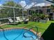 A screened-in pool area featuring lounge chairs, a fire pit, and lush landscaping creates an outdoor oasis at 18702 Van Nuys Cir, Port Charlotte, FL 33948