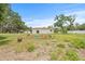 View of the home's backyard with a garden area and covered parking under mature trees at 2233 Rightaway Ln, Plant City, FL 33565